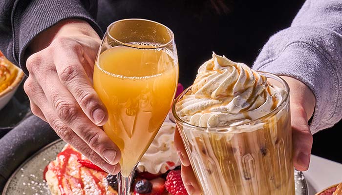 ERA Cafe in Waunakee, WI Two hands hold drinks over fruit-topped waffles at the Best Breakfast in Waunakee, Wisconsin.