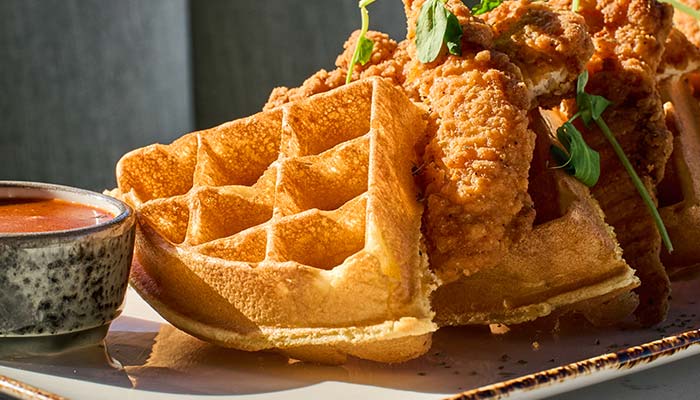 ERA Cafe in Waunakee, WI Chicken and waffles with sauce, garnished with greens—Best Breakfast in Waunakee Wisconsin.