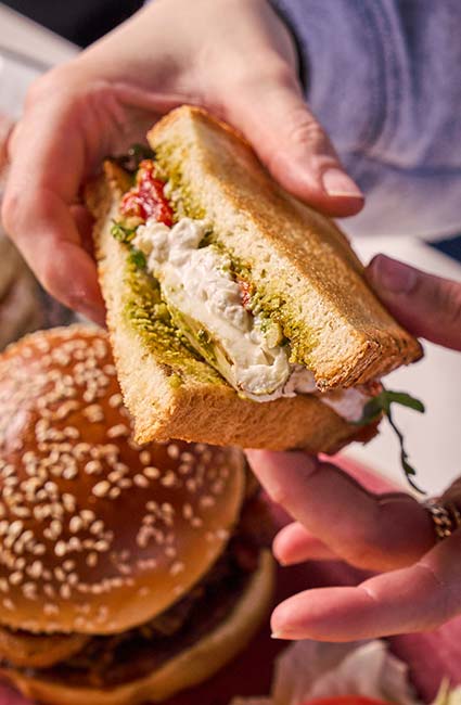 ERA Cafe in Waunakee, WI Hands holding a pesto, cheese, and tomato sandwich at Breakfast Brunch & Lunch in Waunakee Wisconsin.