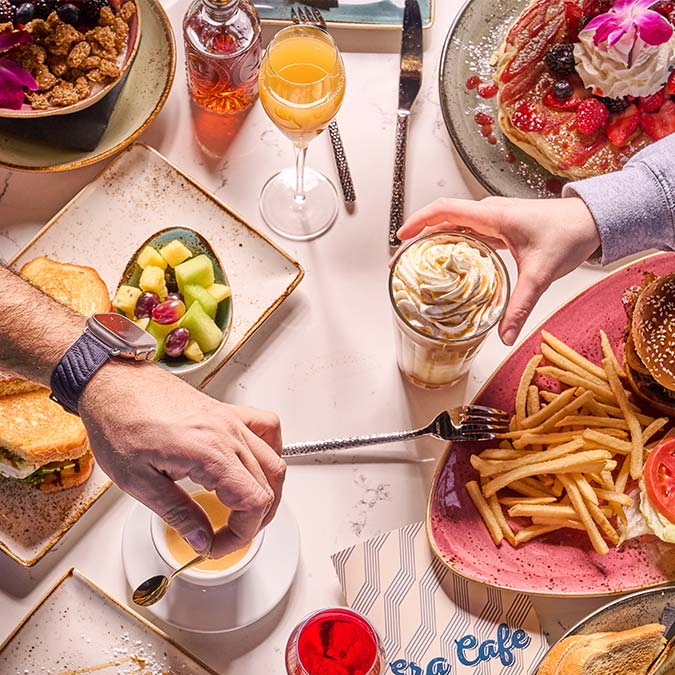 ERA Cafe in Waunakee, WI Hands reaching for food at Breakfast Brunch & Lunch in Waunakee Wisconsin—burgers, pancakes, and more.