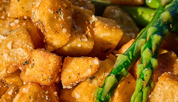 ERA Cafe in Waunakee, WI Close-up of crispy seasoned potato cubes with asparagus spears, perfect for lunch in Wausau Wisconsin.